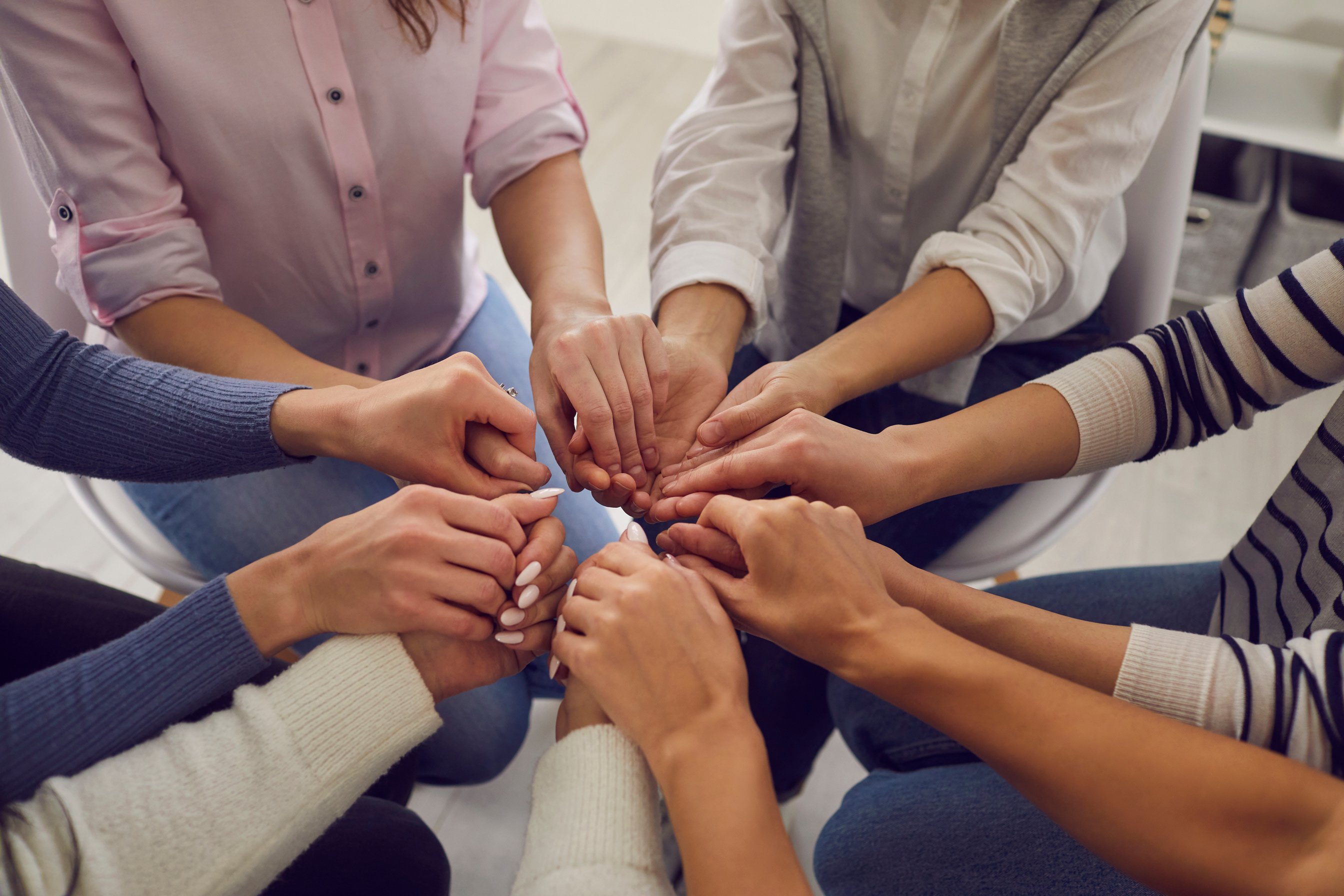 Group of Women Sitting Together and Holding Hands, Demonstrating Support and Solidarity